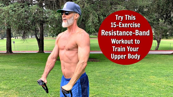 Older, muscled man works out in the park using a resistance band.