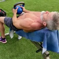Mature male athlete does kettlebell pullover on an incline bench during Back Day.