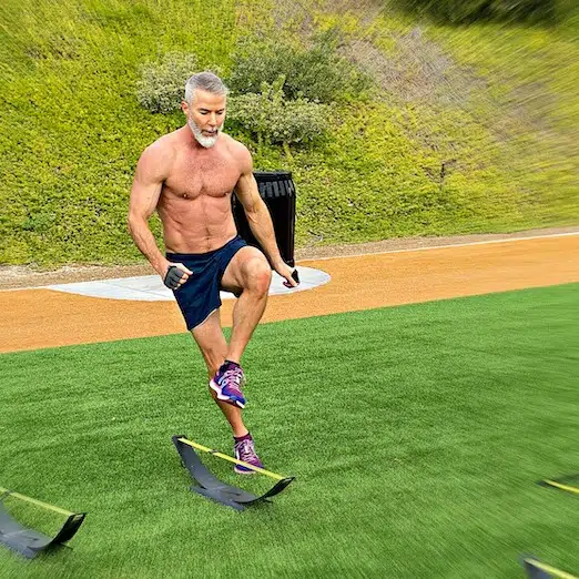 Mature male athlete doing hurdle speed drills at the park on Leg Day.