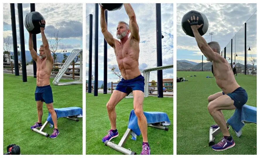 Athlete does overhead squat exercise with weighted medicine ball on leg day.
