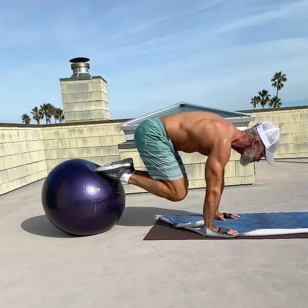 Senior male does core exercises with stability ball to warm up for a dumbbell workout.