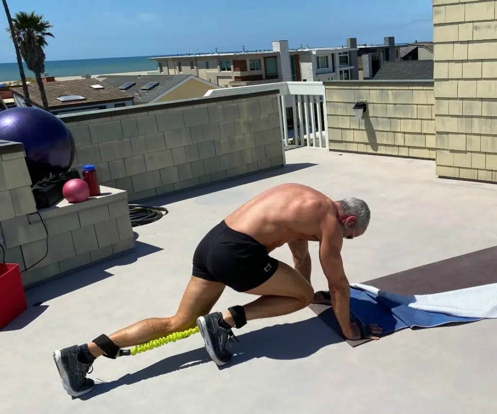 Older man does mountain climbers leg exercises with resistance bands.