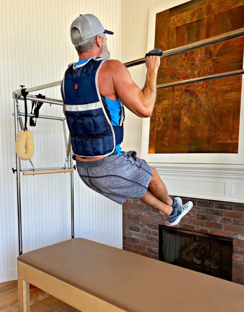 Man doing pull-ups exercise in weighted vest.