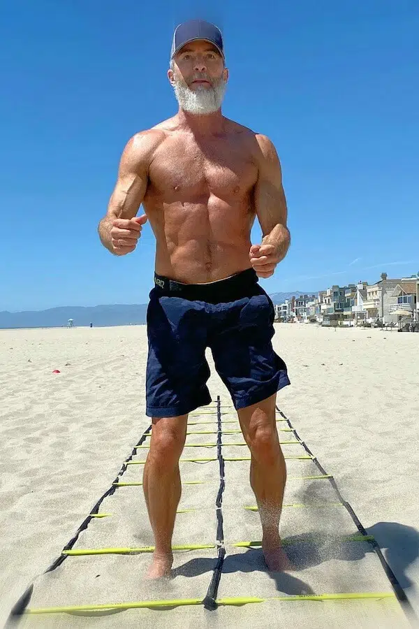 Dane Findley, fitness influencer and health blogger, does speed ladder drills at beach, barefoot in the sand.