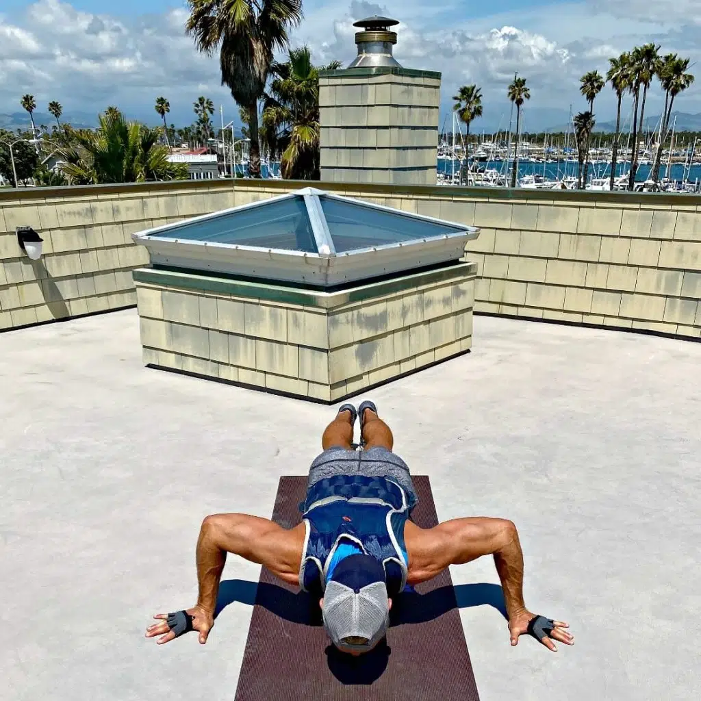 Wide-stance push-ups in a fitness vest for creating sculpted arms and powerful chest.