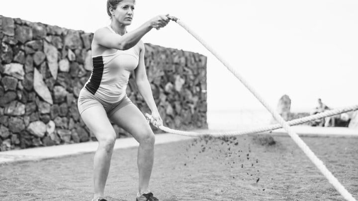 mature female athlete trains with battle rope