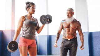 Mature, fit couple doing dumbbell workout.