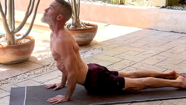 Dane Findley, age 57, does cobra yoga poses for flexibility and range of motion.