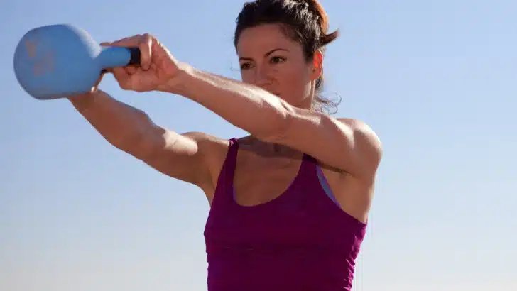 Healthy woman using kettlebell to do Eastern European training exercises.
